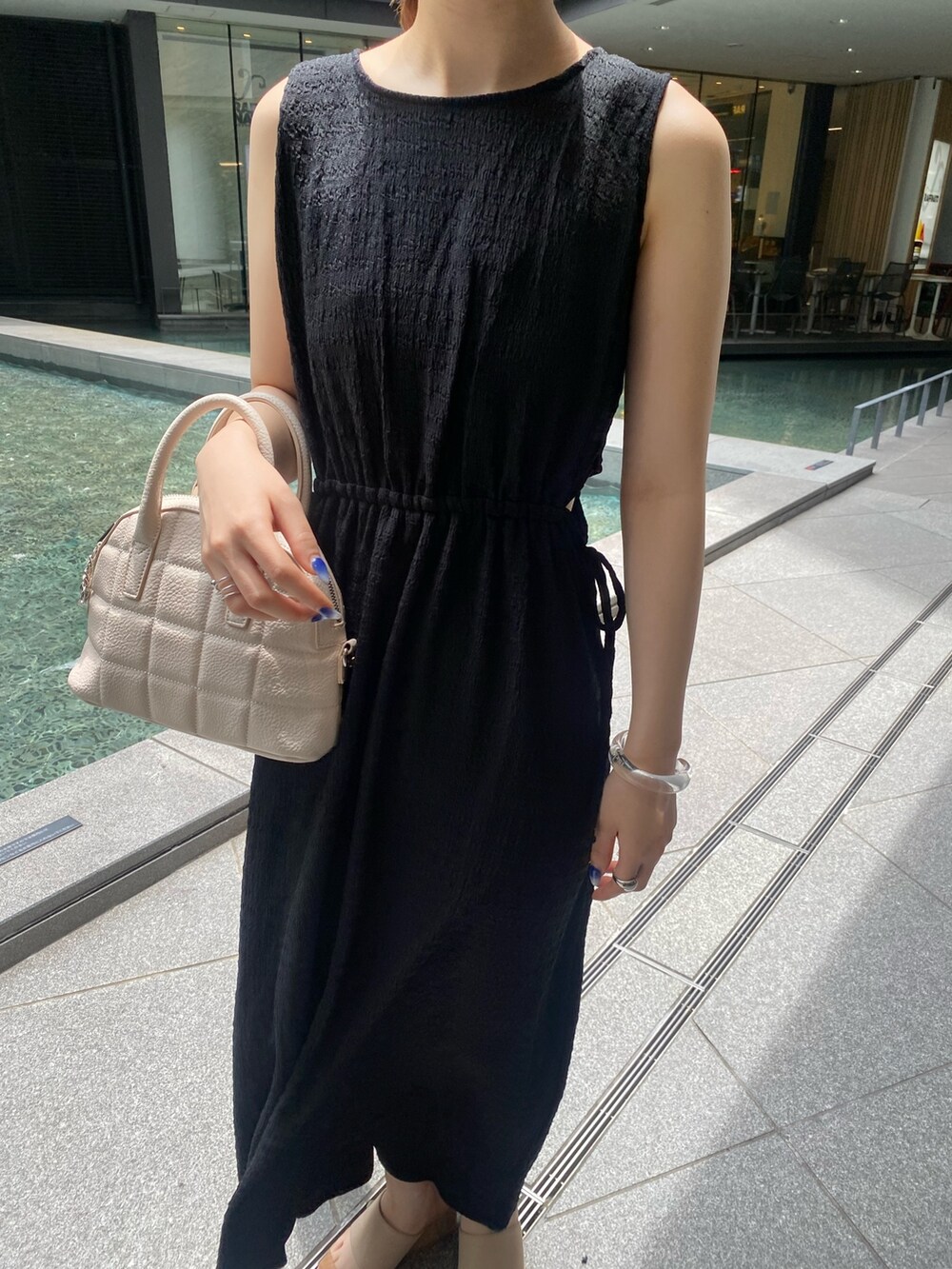 ブラック系のワンピース、グレー系のサンダル、ホワイト系のショルダーバッグを着用したレディースの夏コーディネートの4枚目の写真