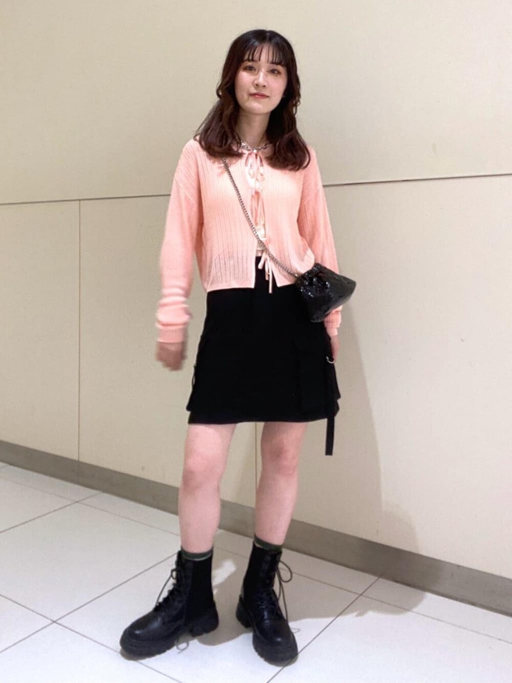 ホワイト系のキャミソール、ピンク系のカーディガン/ボレロ、ブラック系のスカートを着用したレディースの春コーディネートの2枚目の写真
