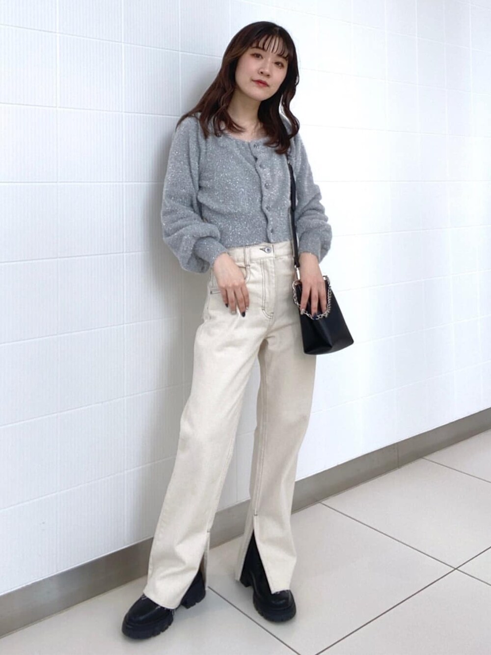 グレー系のニット/セーター、ホワイト系のデニムパンツ、ブラック系のショルダーバッグを着用したレディースの冬コーディネートの2枚目の写真