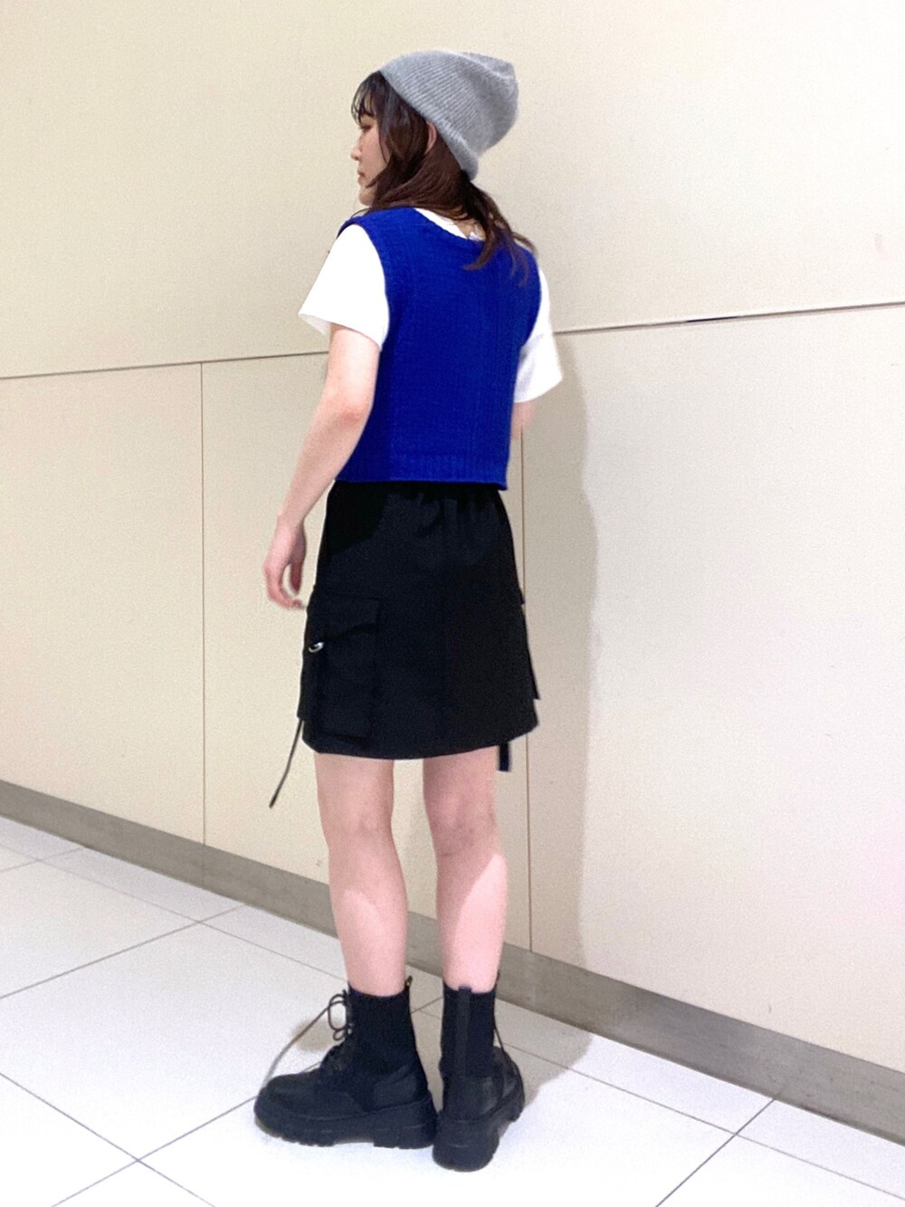 ブルー系のベスト、ホワイト系のTシャツ/カットソー、ブラック系のスカートを着用したレディースの春コーディネートの2枚目の写真