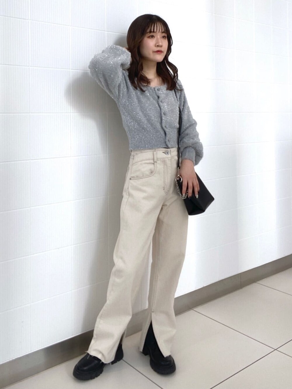 グレー系のニット/セーター、ホワイト系のデニムパンツ、ブラック系のショルダーバッグを着用したレディースの冬コーディネートの3枚目の写真