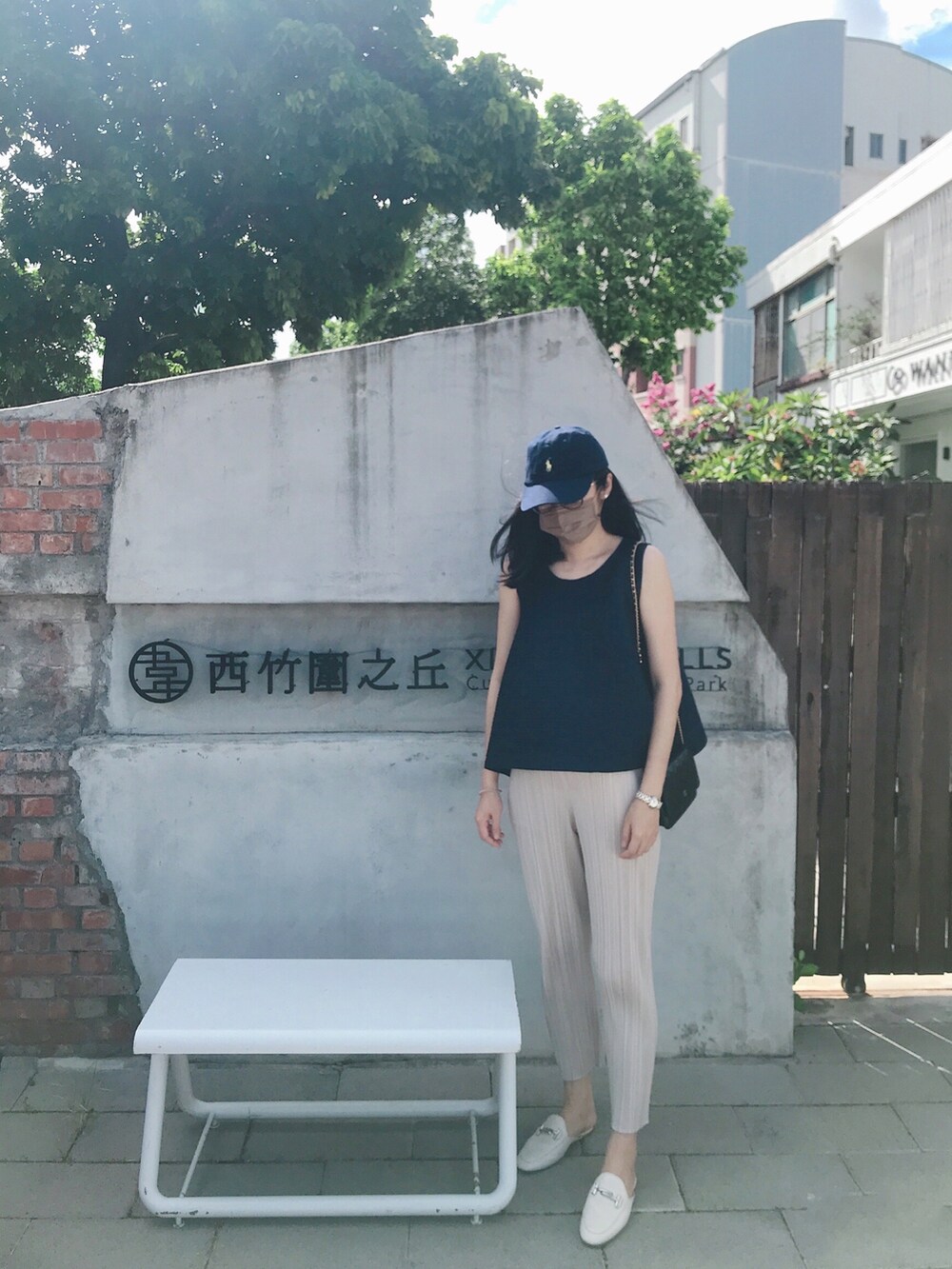 ブルー系のトップス、ブラック系のショルダーバッグ、ベージュ系のパンツを着用したレディースの夏コーディネートの2枚目の写真