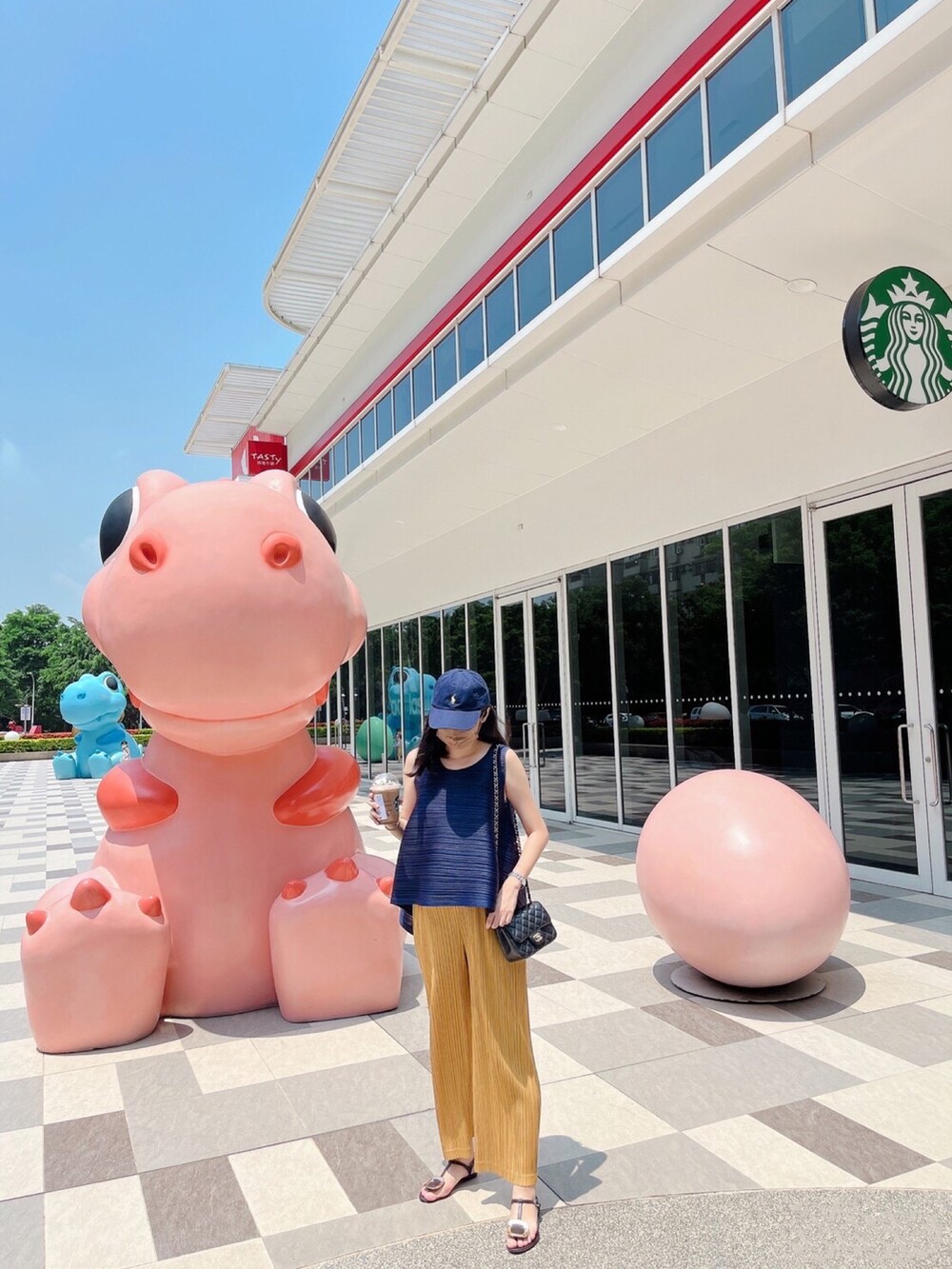ブルー系のトップス、ブラック系のショルダーバッグ、ゴールド系のパンツを着用したレディースの夏コーディネートの3枚目の写真