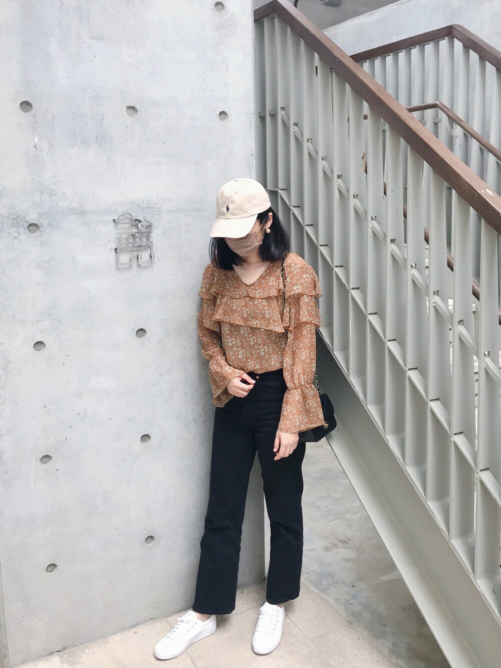 ブラック系のバッグ、ブラック系のデニムパンツ、ホワイト系のシューズを着用したレディースの春コーディネートの2枚目の写真