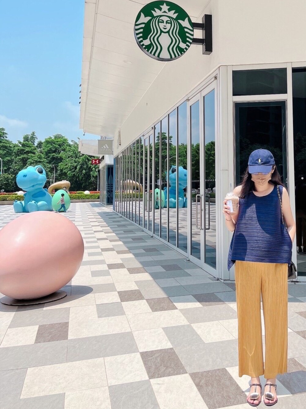 ブルー系のトップス、ブラック系のショルダーバッグ、ゴールド系のパンツを着用したレディースの夏コーディネートの2枚目の写真