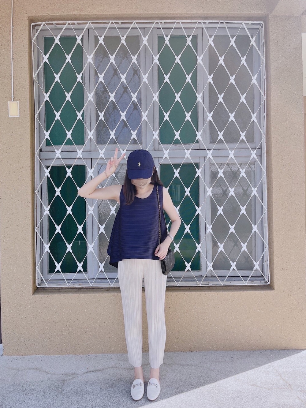 ブルー系のトップス、ブラック系のショルダーバッグ、ベージュ系のパンツを着用したレディースの夏コーディネートの3枚目の写真