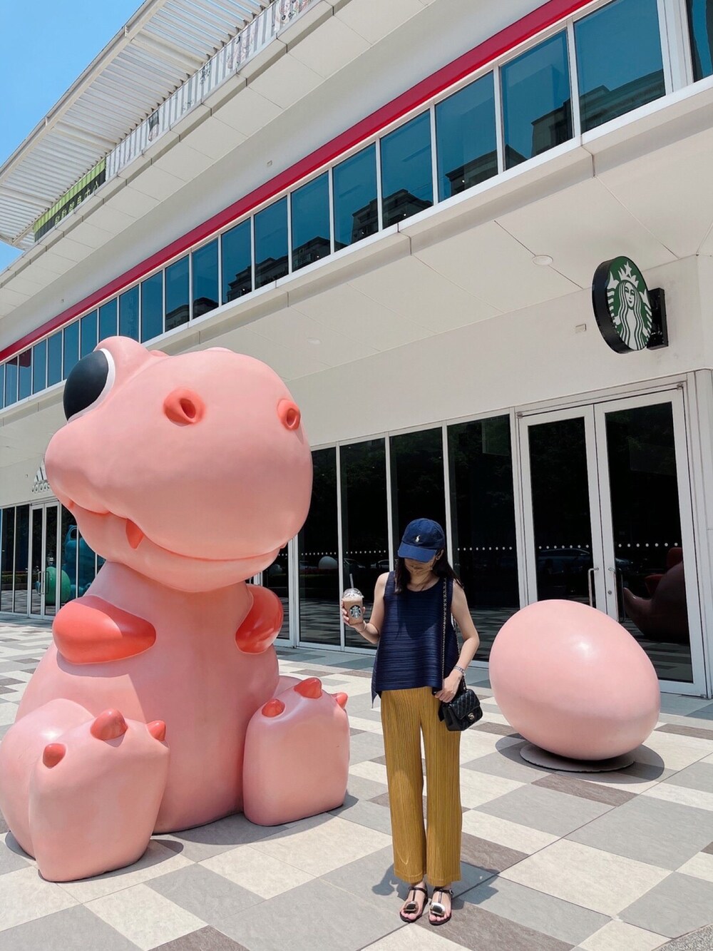 ブルー系のトップス、ブラック系のショルダーバッグ、ゴールド系のパンツを着用したレディースの夏コーディネートの4枚目の写真