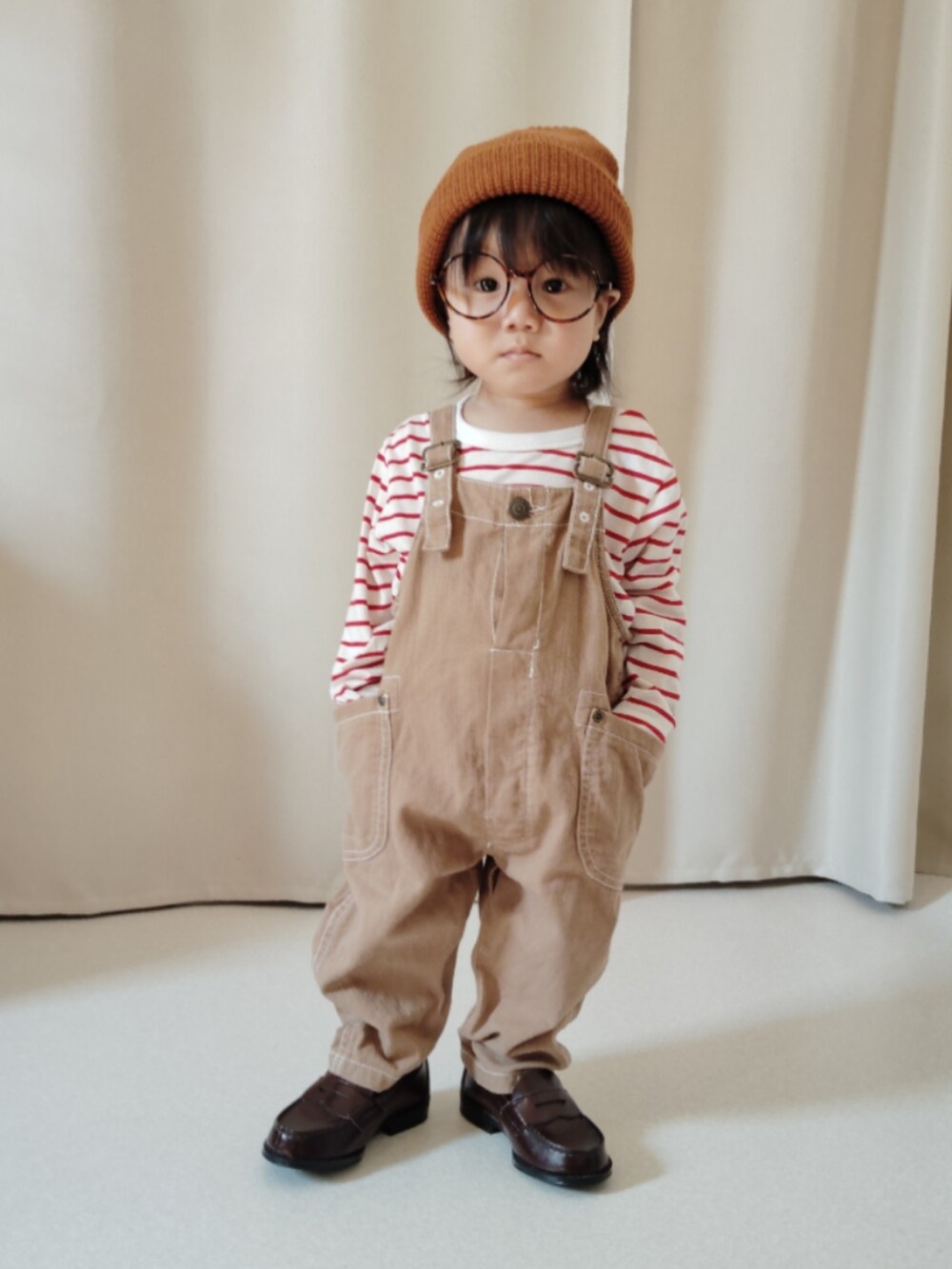 ベージュ系のサロペット/オーバーオール、レッド系のTシャツ/カットソー、ブラウン系のローファーを着用したキッズの秋コーディネートの2枚目の写真