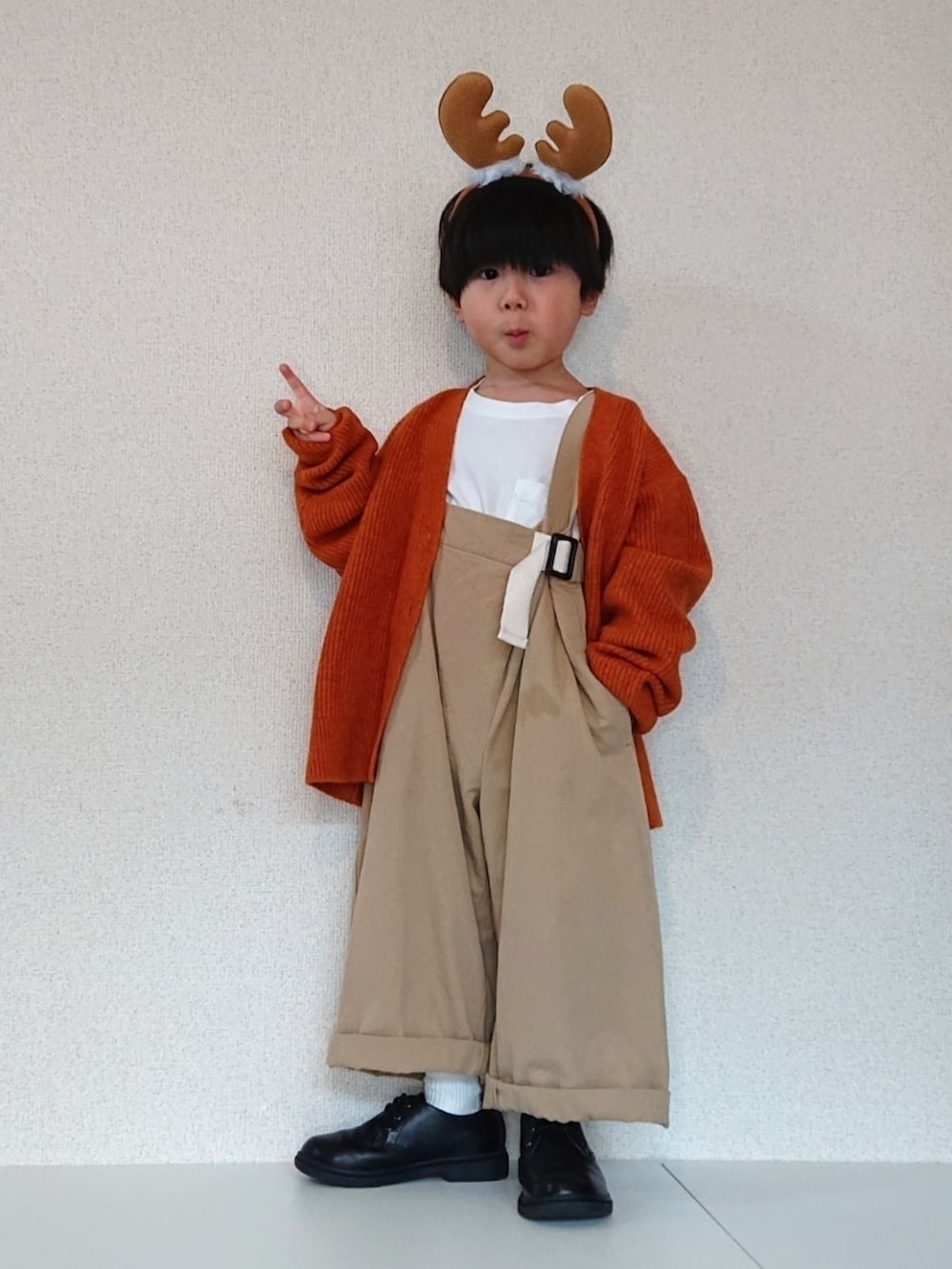 オレンジ系のカーディガン/ボレロ、ベージュ系のサロペット/オーバーオール、ホワイト系のTシャツ/カットソーを着用したキッズの冬コーディネートの3枚目の写真