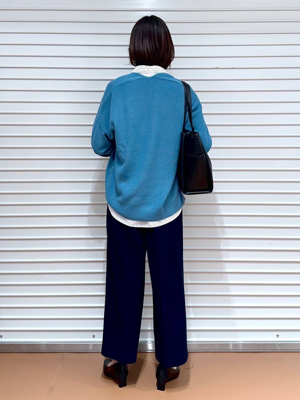 ブラック系のトートバッグ、ブルー系のニット/セーター、ホワイト系のシャツ/ブラウスを着用したレディースの春コーディネートの4枚目の写真