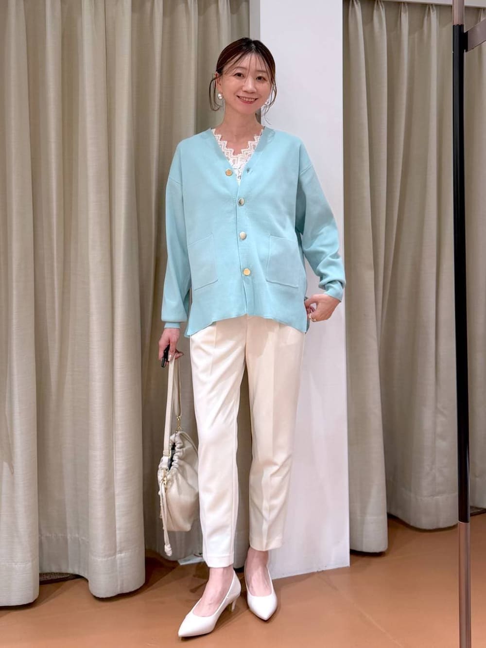 ベージュ系のパンプス、グリーン系のカーディガン/ボレロ、ホワイト系のハンドバッグを着用したレディースの冬コーディネートの2枚目の写真