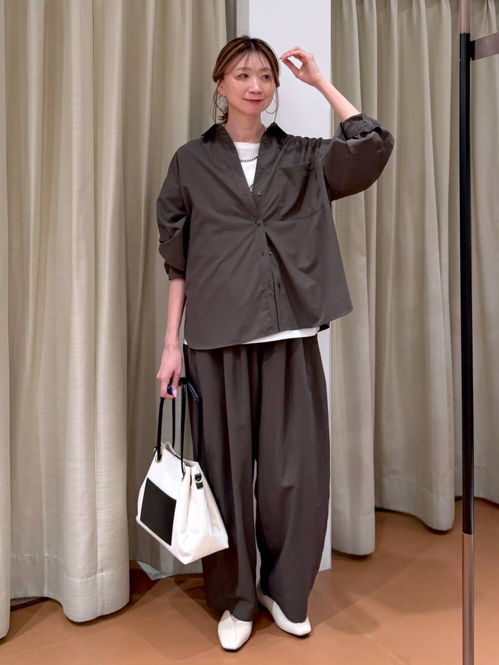 ホワイト系のパンプス、ブラック系のトートバッグ、ブラウン系のシャツ/ブラウスを着用したレディースの春コーディネートの2枚目の写真