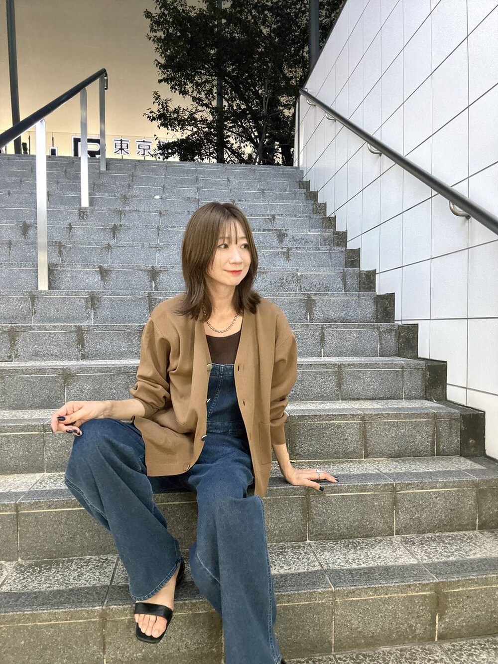 ブラウン系のニット/セーター、ブラウン系のカーディガン/ボレロ、ブルー系のサロペット/オーバーオールを着用したレディースの夏コーディネートの2枚目の写真