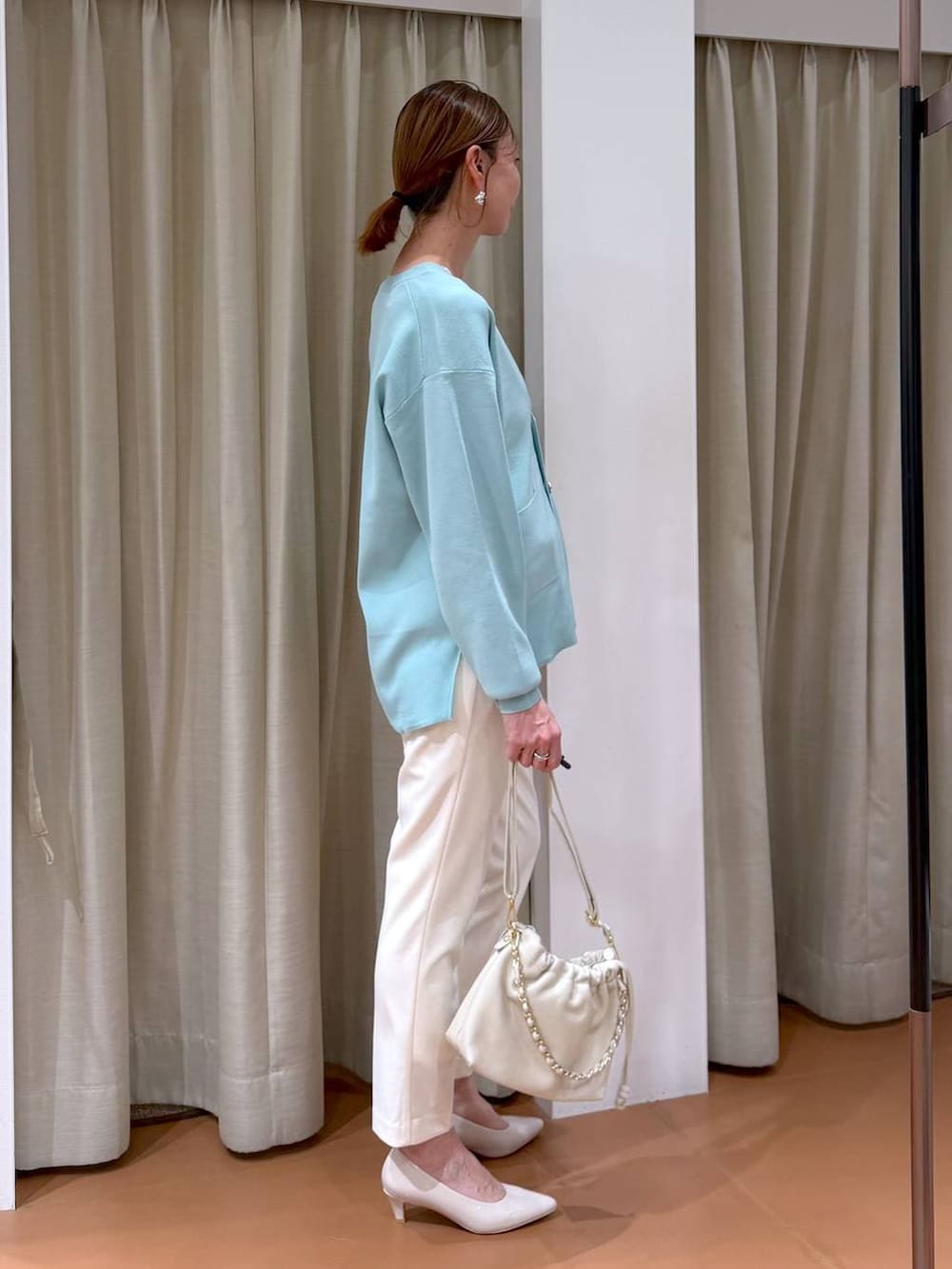 ベージュ系のパンプス、グリーン系のカーディガン/ボレロ、ホワイト系のハンドバッグを着用したレディースの冬コーディネートの5枚目の写真