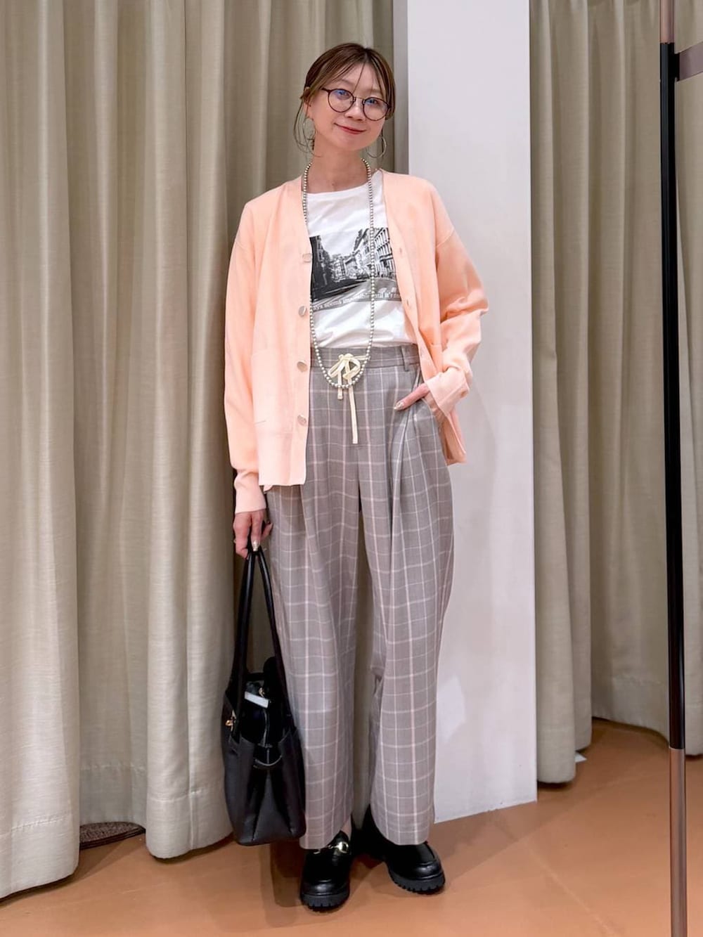 ピンク系のカーディガン/ボレロ、ブラック系のローファー、ブラック系のハンドバッグを着用したレディースの冬コーディネートの2枚目の写真