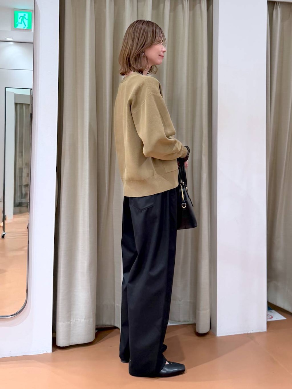 ブラック系のハンドバッグ、ブラック系のパンプス、ブラック系のTシャツ/カットソーを着用したレディースの冬コーディネートの5枚目の写真