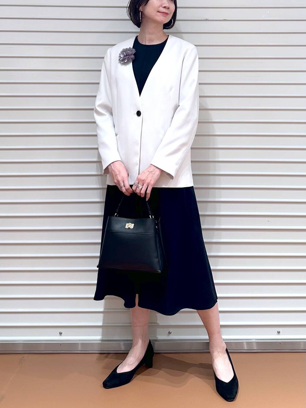 ベージュ系のノーカラージャケット、ブルー系のワンピース、ブラック系のハンドバッグを着用したレディースの冬コーディネートの5枚目の写真