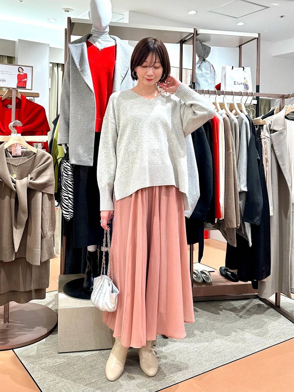 グレー系のニット/セーター、ベージュ系のブーツ、ピンク系のスカートを着用したレディースの冬コーディネートの2枚目の写真