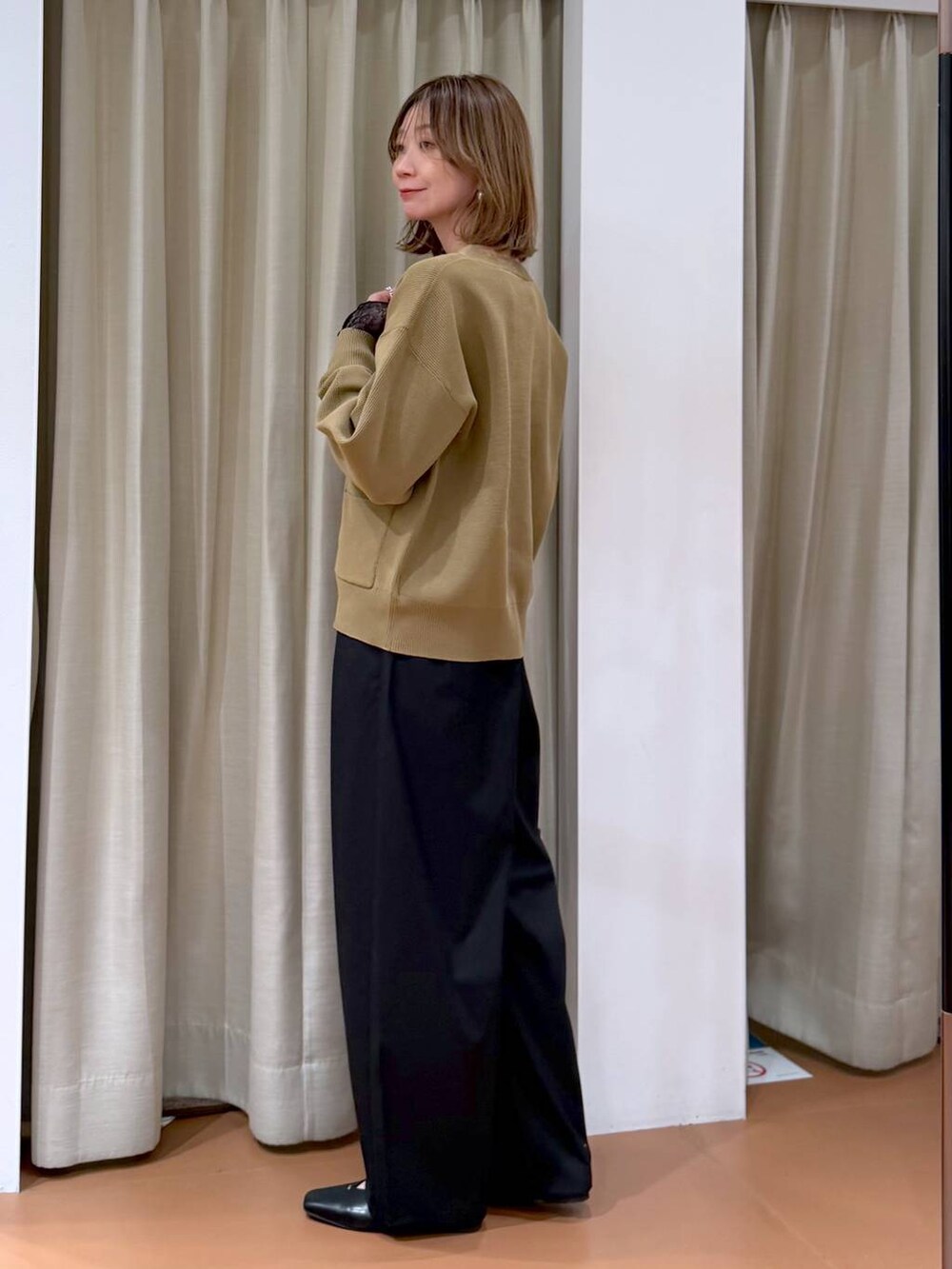 ブラック系のハンドバッグ、ブラック系のパンプス、ブラック系のTシャツ/カットソーを着用したレディースの冬コーディネートの3枚目の写真