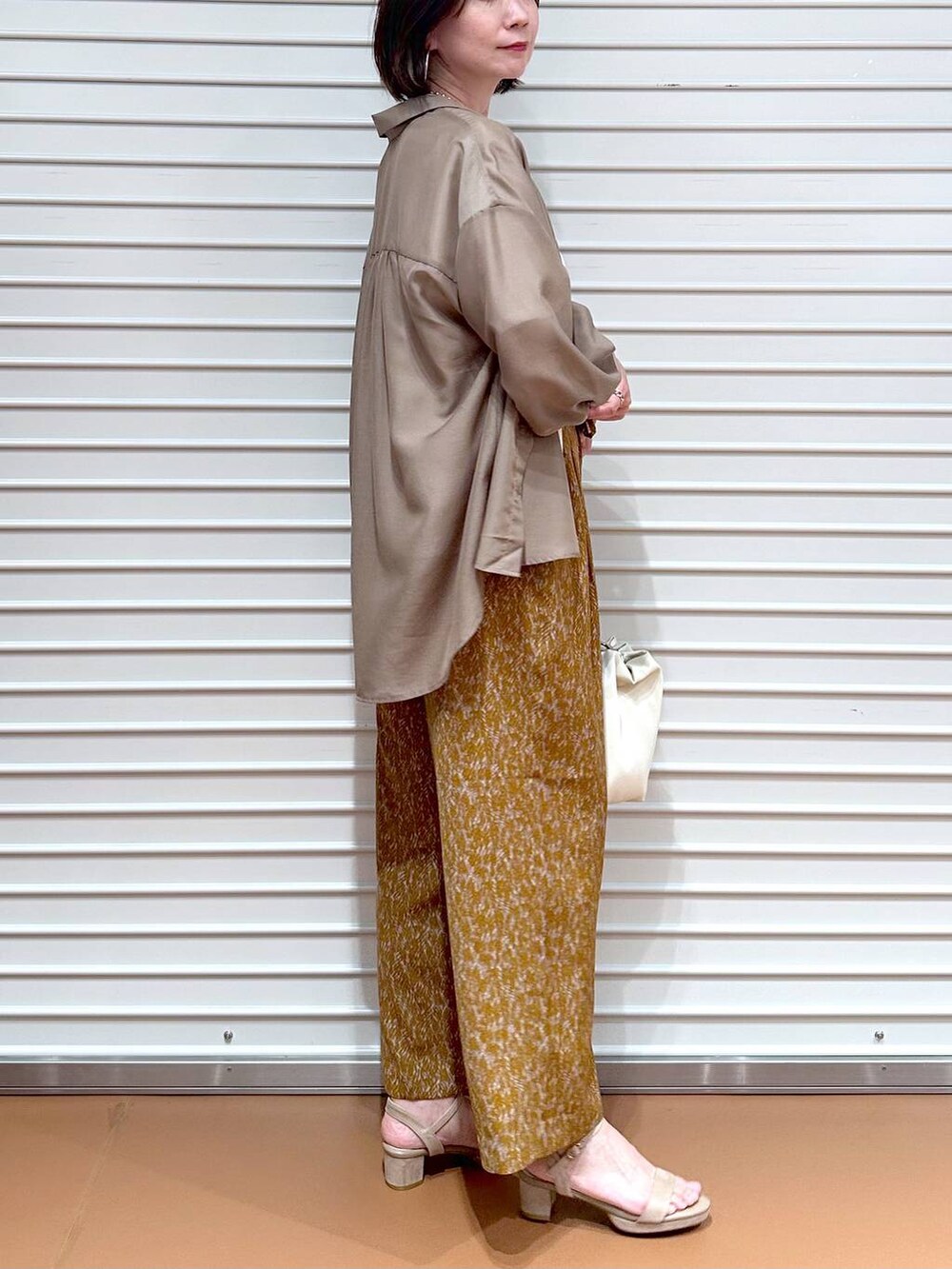 ベージュ系のサンダル、ブラウン系のその他パンツ、ホワイト系のTシャツ/カットソーを着用したレディースの秋コーディネートの6枚目の写真