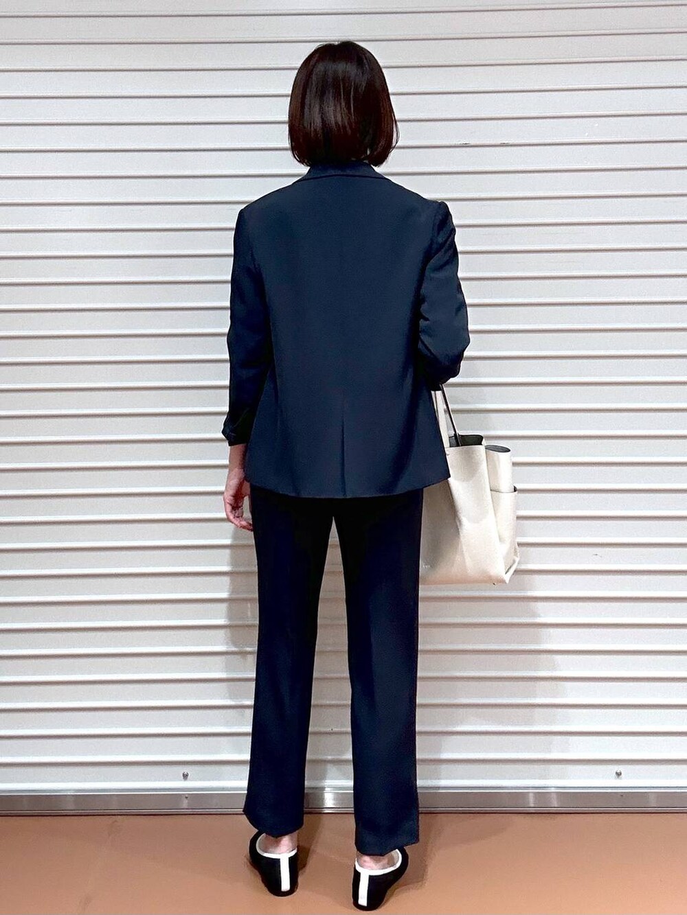 ブラック系のパンプス、ホワイト系のトートバッグ、ブルー系のその他パンツを着用したレディースの春コーディネートの3枚目の写真