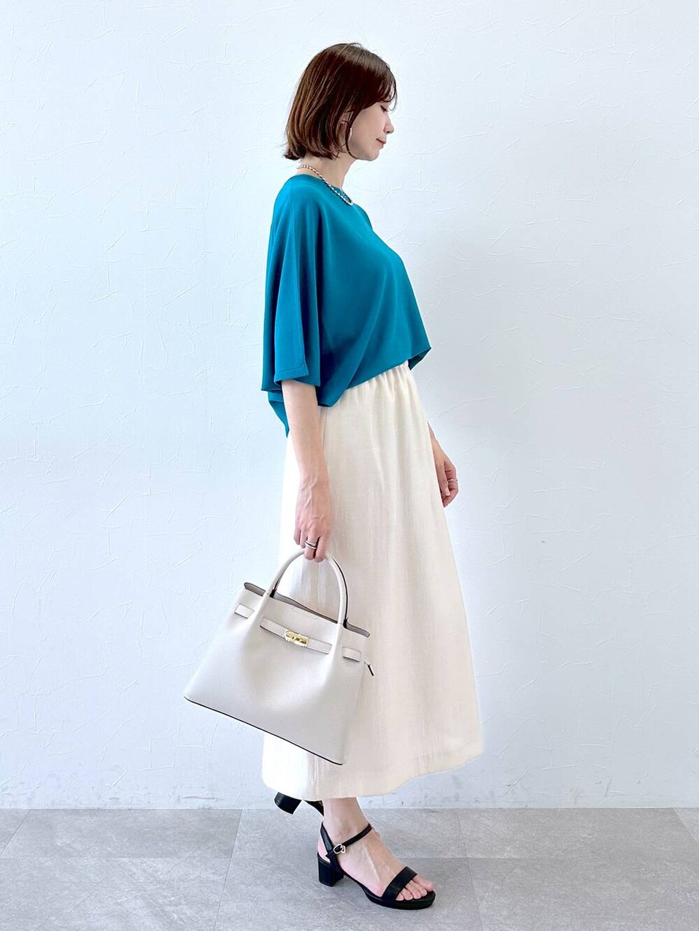 ホワイト系のスカート、ブラック系のサンダル、ブルー系のニット/セーターを着用したレディースの夏コーディネートの3枚目の写真