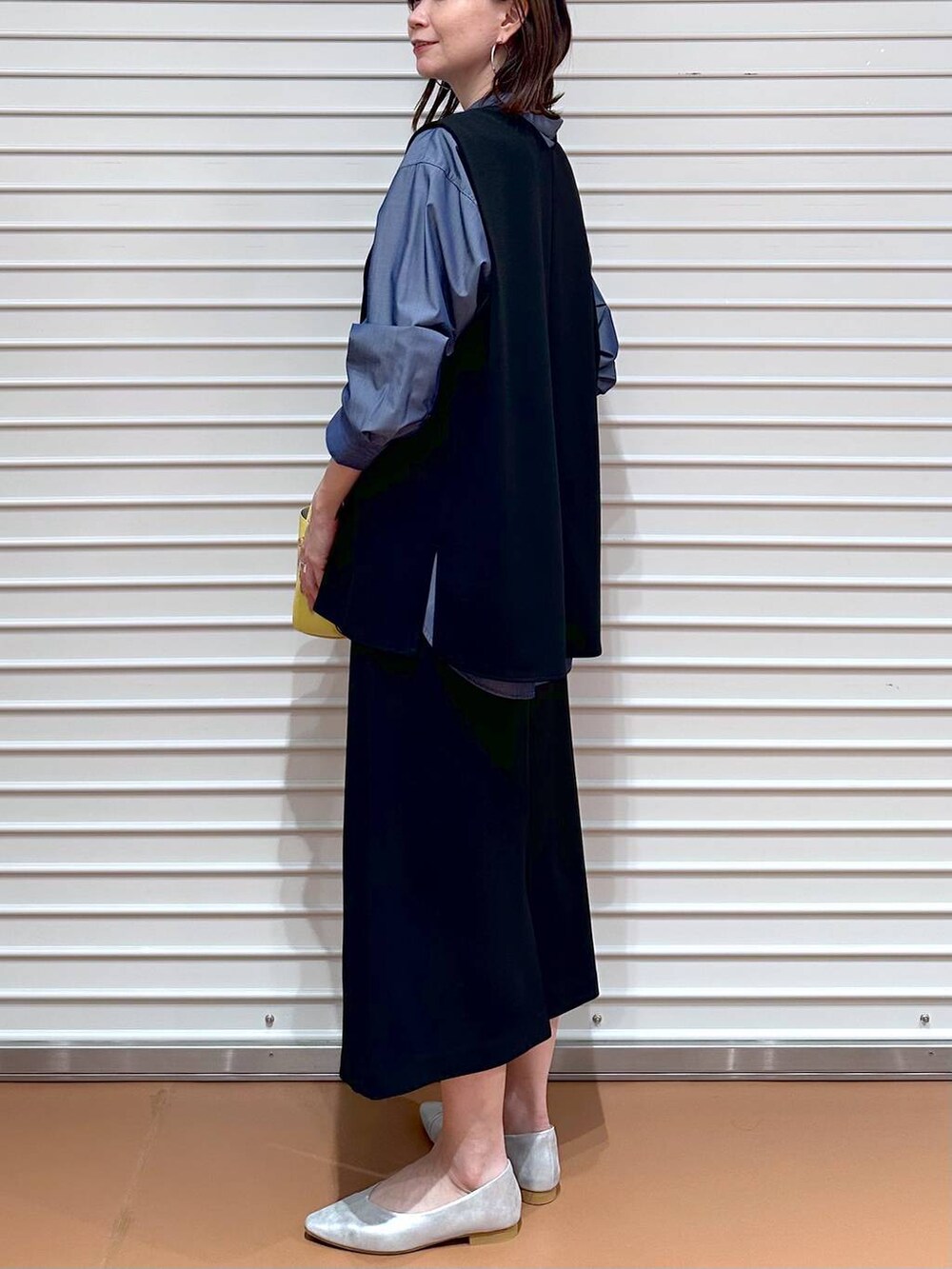 イエロー系のハンドバッグ、ブルー系のシャツ/ブラウス、ブラック系のスカートを着用したレディースの冬コーディネートの5枚目の写真