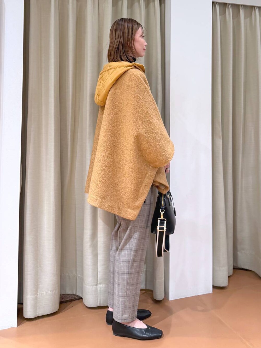 ブラック系のハンドバッグ、ブラック系のスラックス、ブラック系のパンプスを着用したレディースの冬コーディネートの5枚目の写真