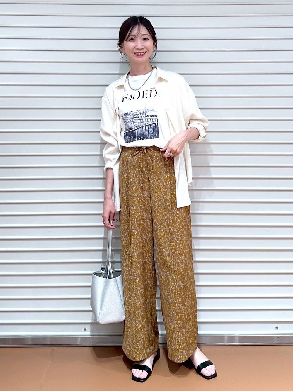 ホワイト系のシャツ/ブラウス、ブラウン系のその他パンツ、ブラック系のサンダルを着用したレディースの夏コーディネートの2枚目の写真