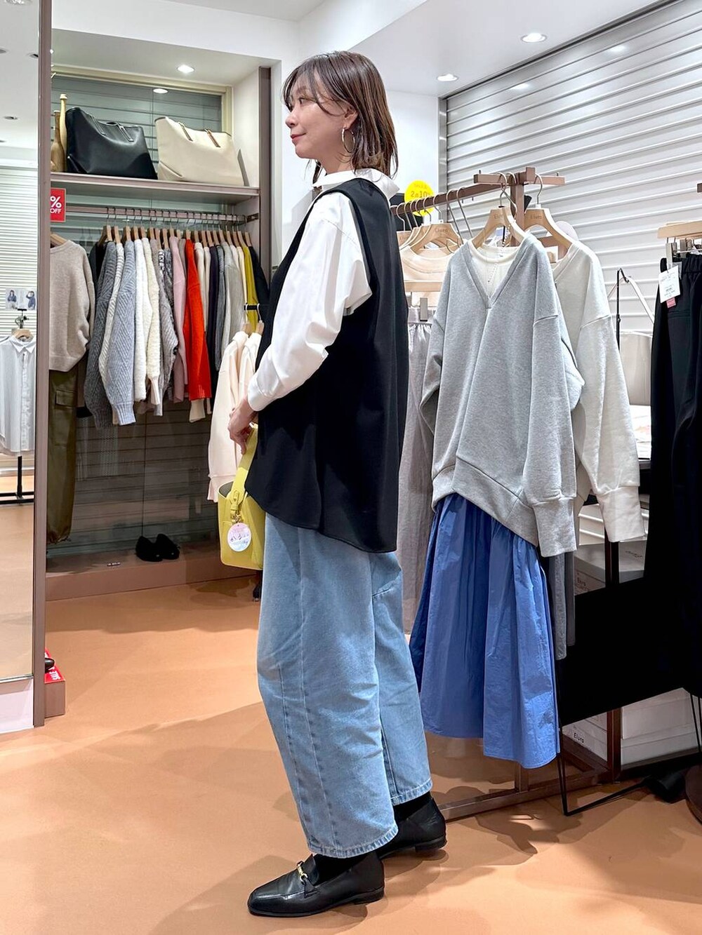 イエロー系のハンドバッグ、ホワイト系のシャツ/ブラウス、ブラック系のローファーを着用したレディースの冬コーディネートの3枚目の写真