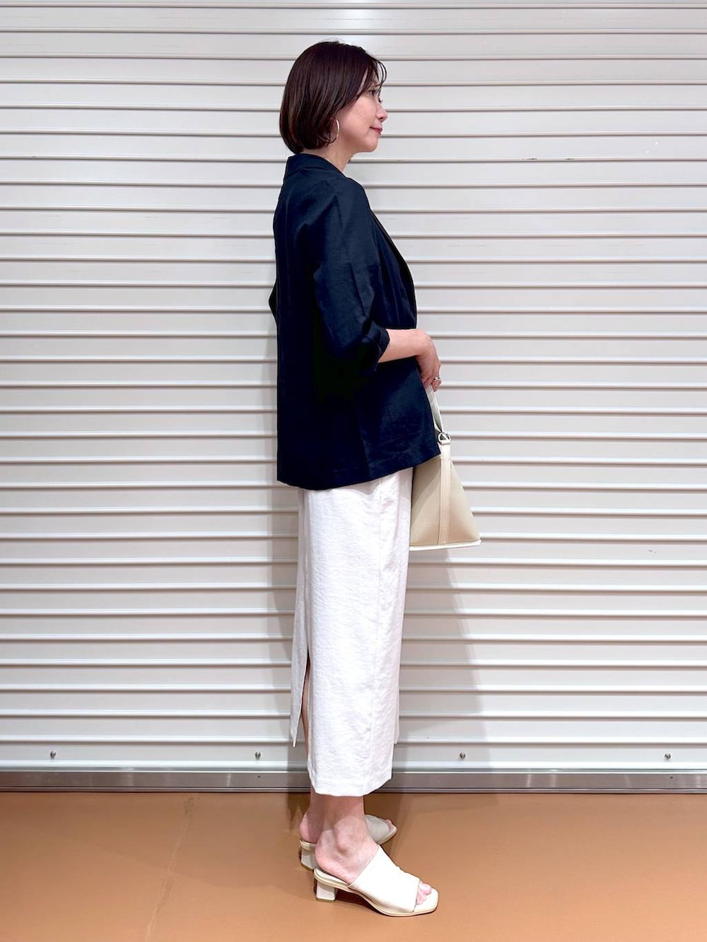 ホワイト系のサンダル、ホワイト系のトートバッグ、グレー系のスカートを着用したレディースの秋コーディネートの3枚目の写真