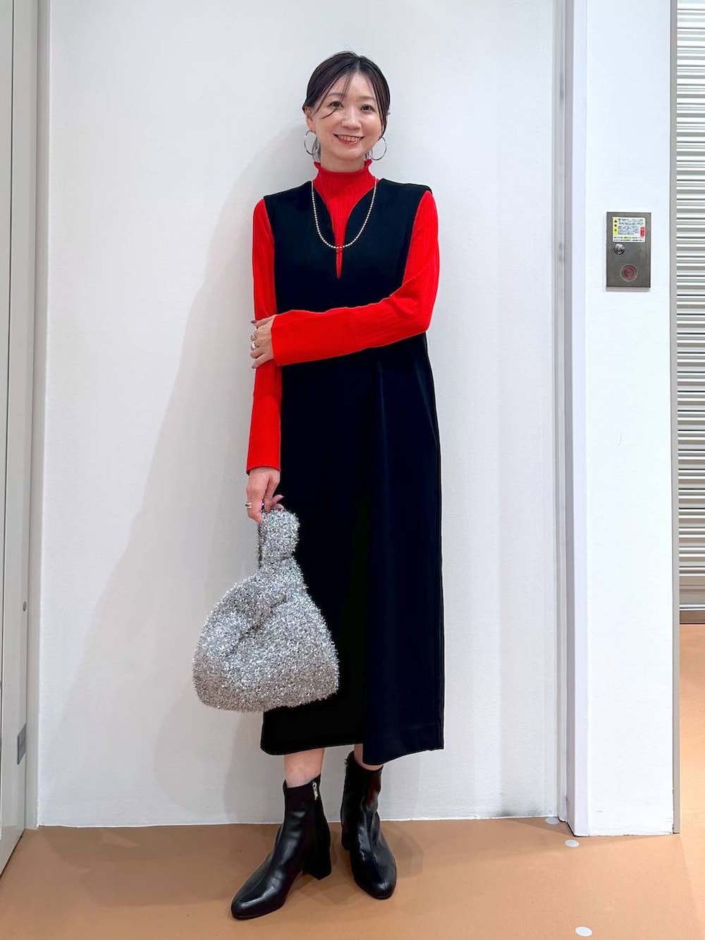 ブラック系のジャンパースカート、ブラック系のブーツ、ブラウン系のノーカラージャケットを着用したレディースの秋コーディネートの3枚目の写真