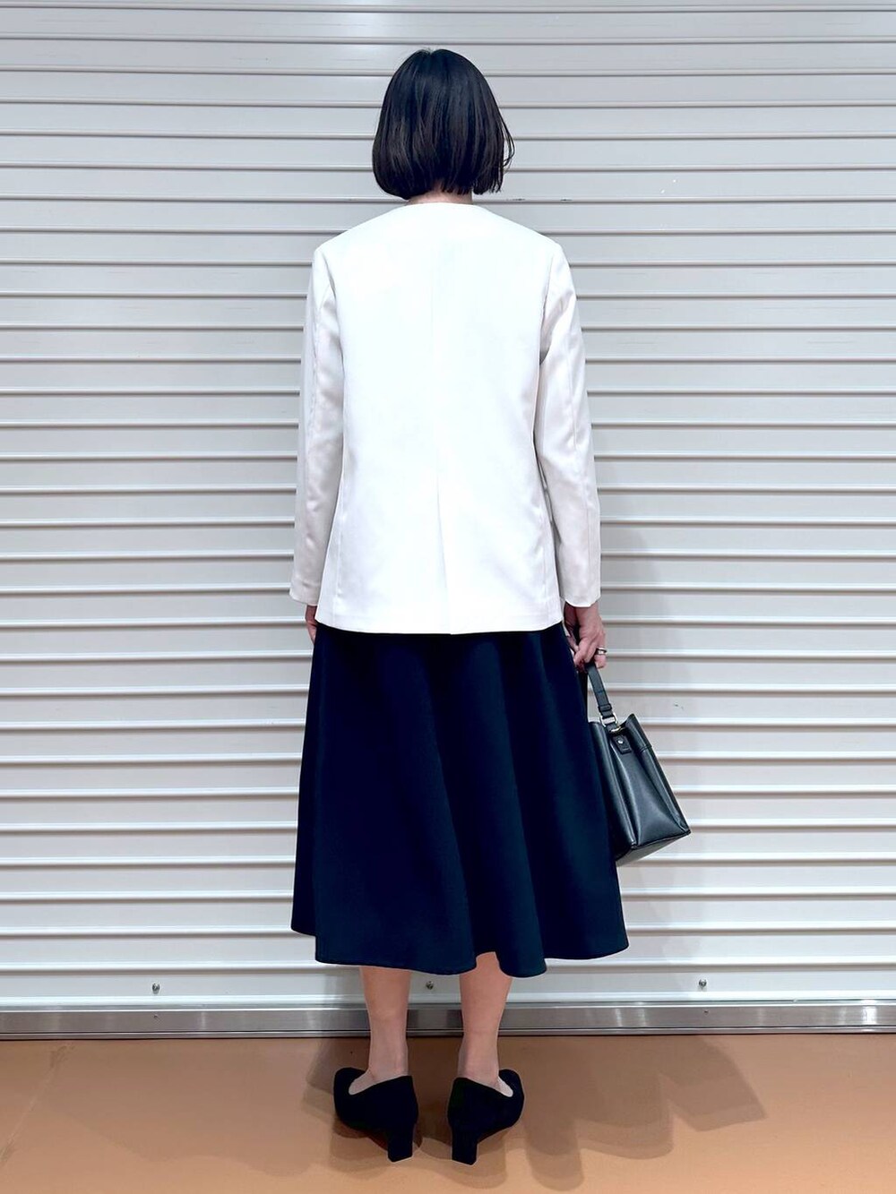 ベージュ系のノーカラージャケット、ブルー系のワンピース、ブラック系のハンドバッグを着用したレディースの冬コーディネートの4枚目の写真