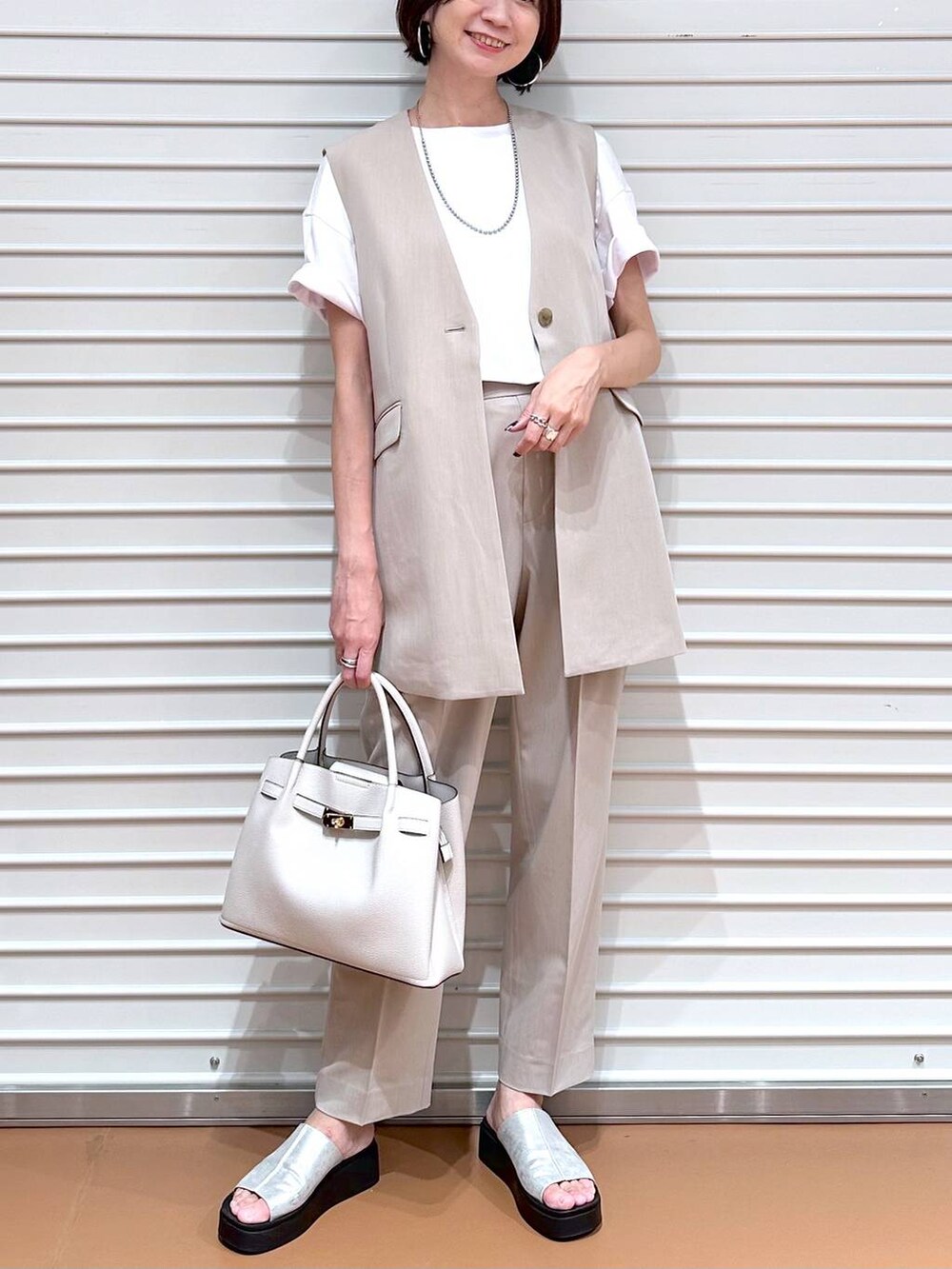 ベージュ系のベスト、シルバー系のサンダル、ホワイト系のTシャツ/カットソーを着用したレディースの夏コーディネートの5枚目の写真