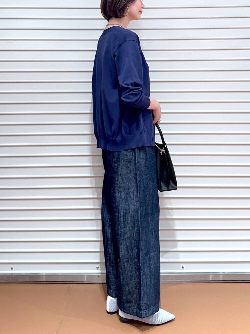 シルバー系のパンプス、ブルー系のデニムパンツ、ブラック系のショルダーバッグを着用したレディースの夏コーディネートの6枚目の写真