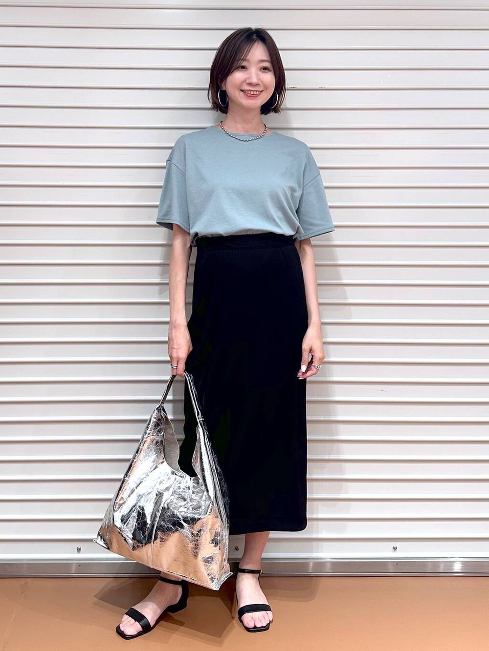 ブラック系のサンダル、ブラック系のスカート、グリーン系のTシャツ/カットソーを着用したレディースの秋コーディネートの2枚目の写真