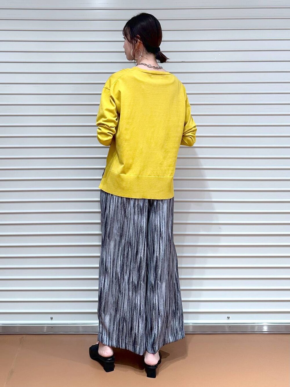 ブラック系のサンダル、グレー系のその他パンツ、イエロー系のニット/セーターを着用したレディースの春コーディネートの4枚目の写真