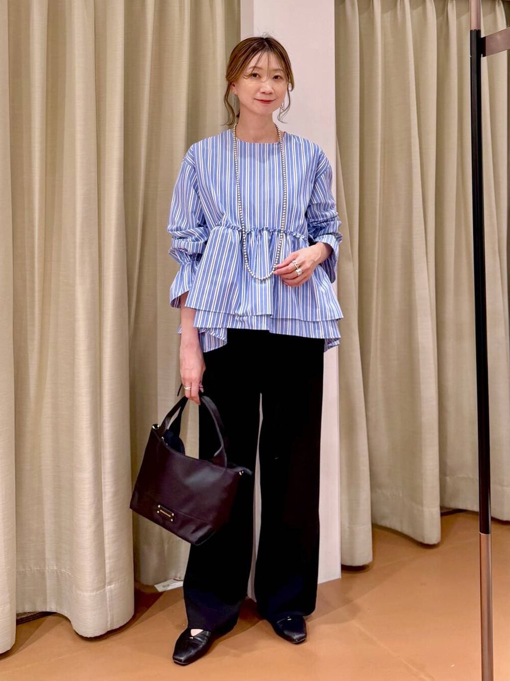 ブラック系のその他パンツ、ブラック系のパンプス、ブルー系のシャツ/ブラウスを着用したレディースの春コーディネートの6枚目の写真