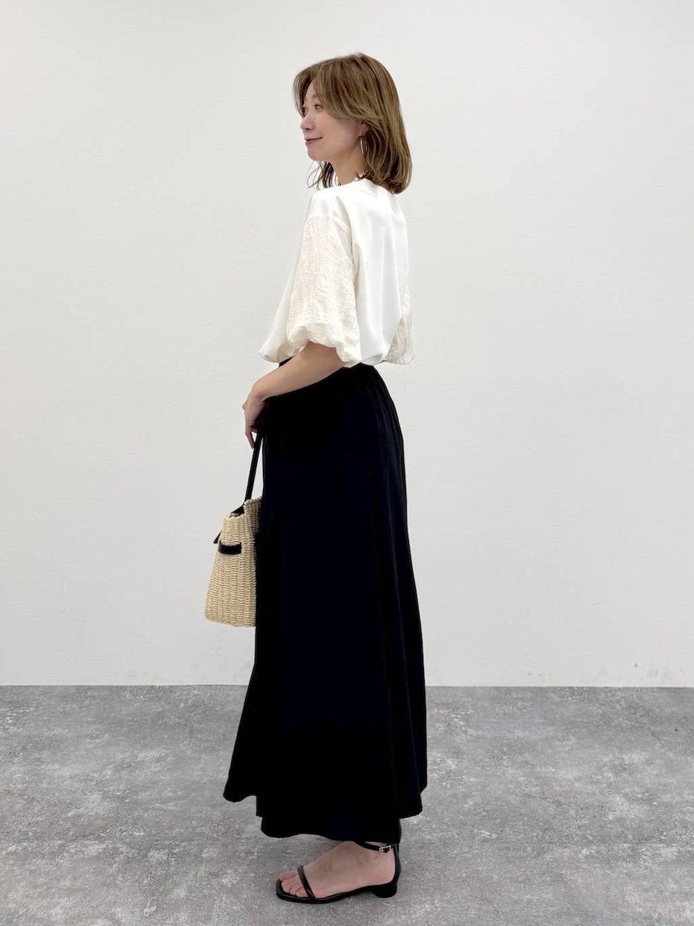 ホワイト系のTシャツ/カットソー、ブラック系のスカート、ゴールド系のネックレスを着用したレディースの春コーディネートの3枚目の写真