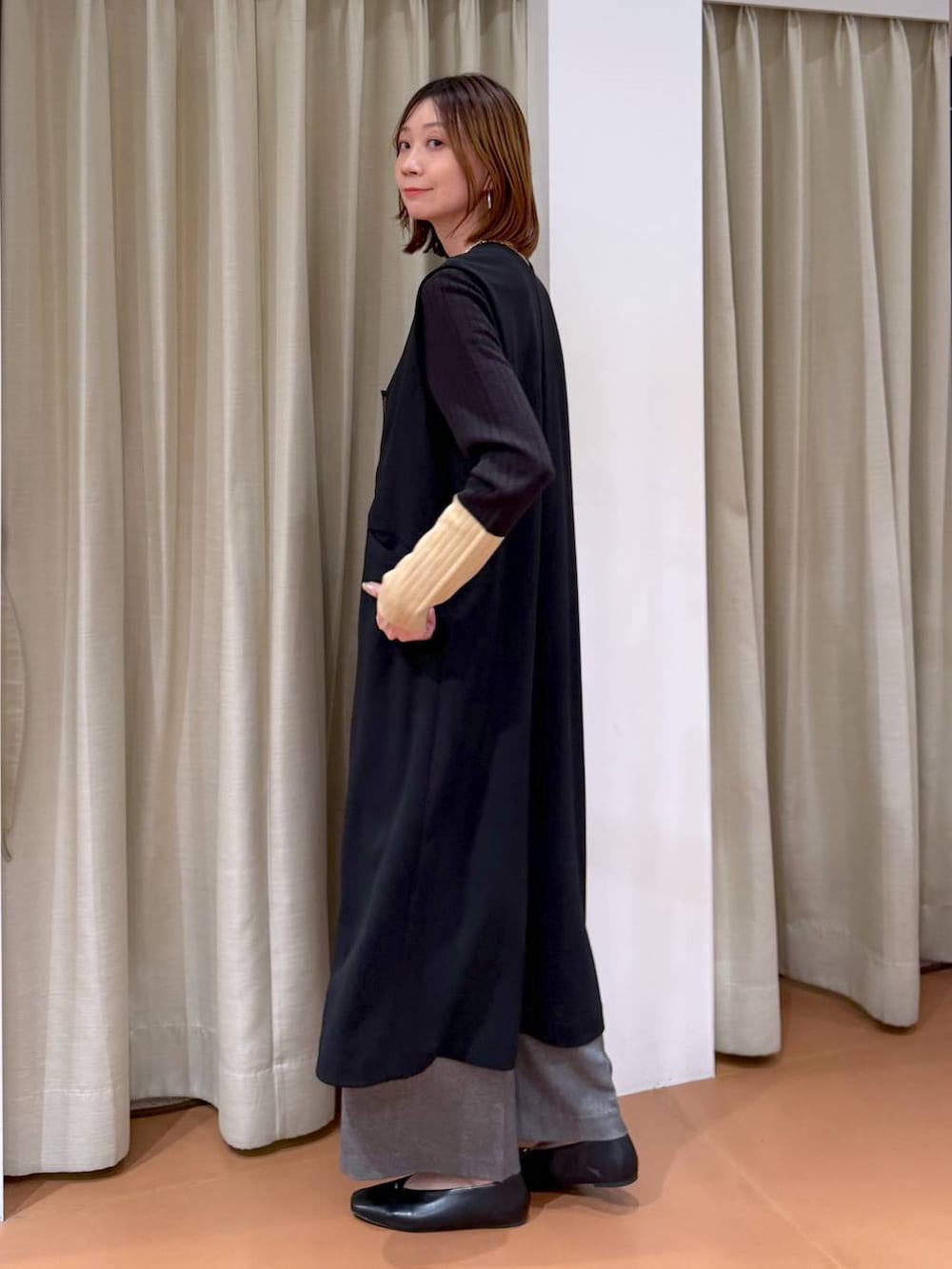 ブラック系のハンドバッグ、グレー系のその他パンツ、ブラック系のパンプスを着用したレディースの冬コーディネートの3枚目の写真