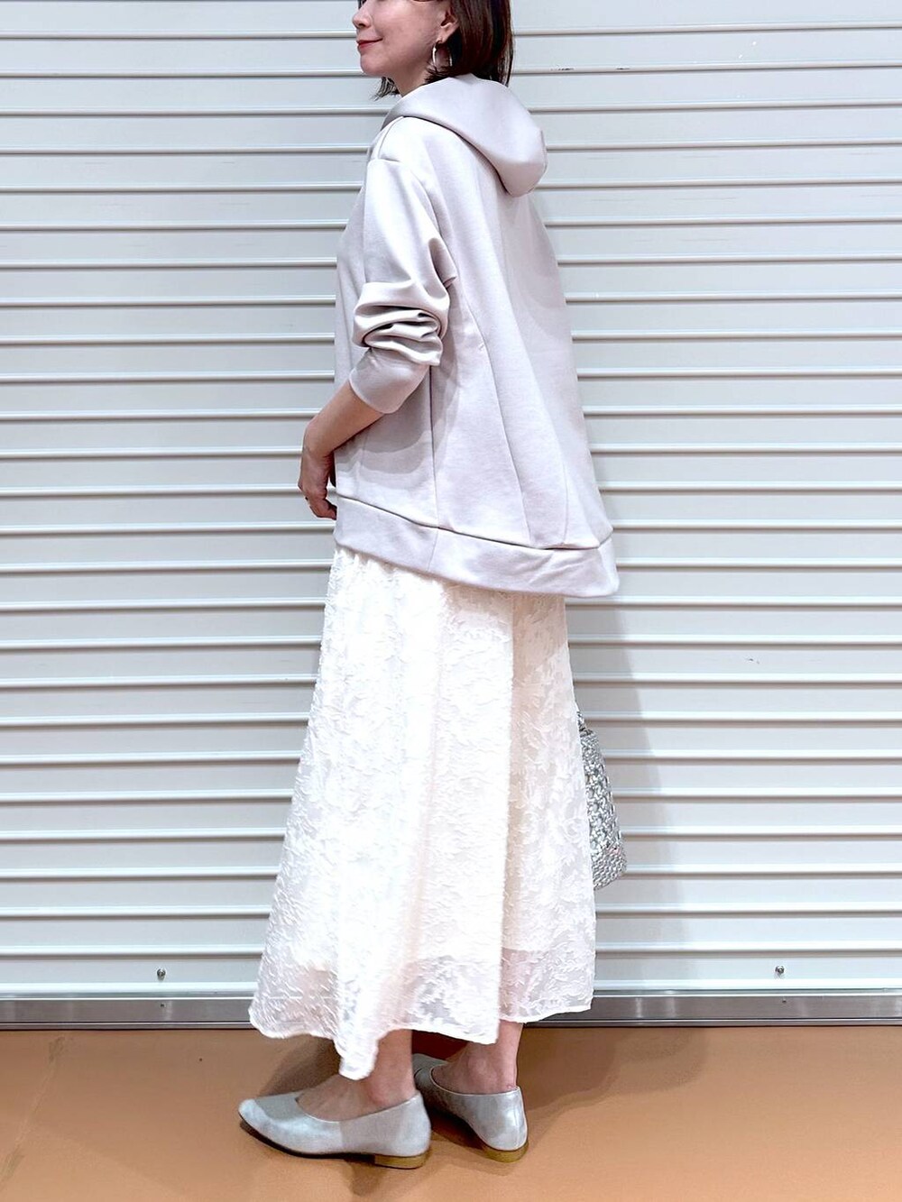 ベージュ系のパーカー、シルバー系のパンプス、ホワイト系のスカートを着用したレディースの春コーディネートの7枚目の写真