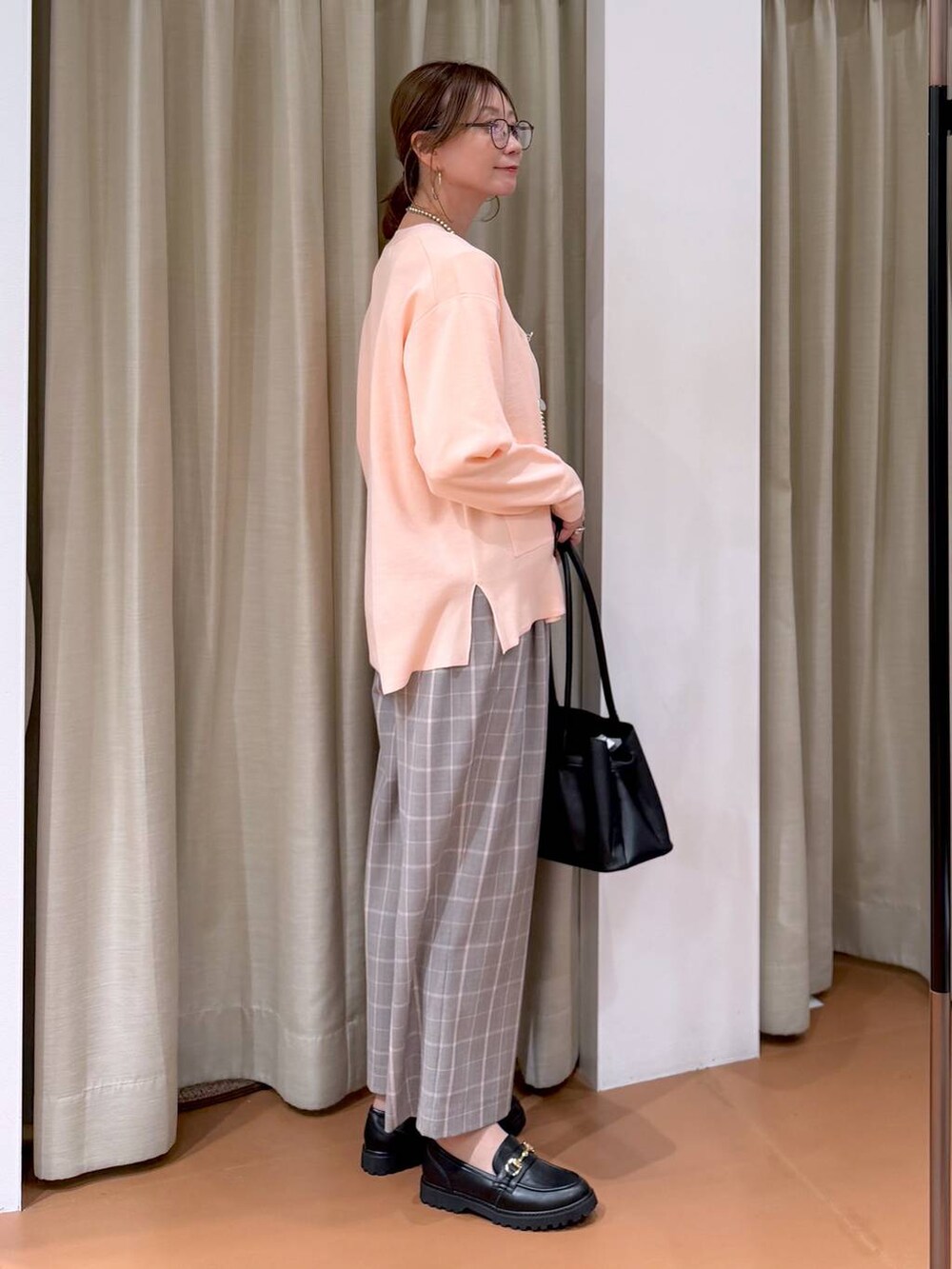 ピンク系のカーディガン/ボレロ、ブラック系のローファー、ブラック系のハンドバッグを着用したレディースの冬コーディネートの3枚目の写真