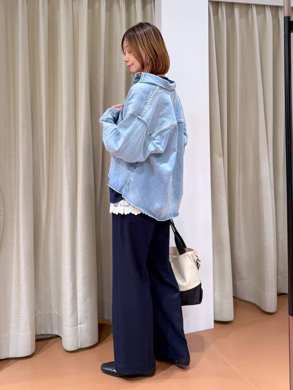 ベージュ系のトートバッグ、ブラック系のパンプス、ホワイト系のタンクトップを着用したレディースの冬コーディネートの3枚目の写真