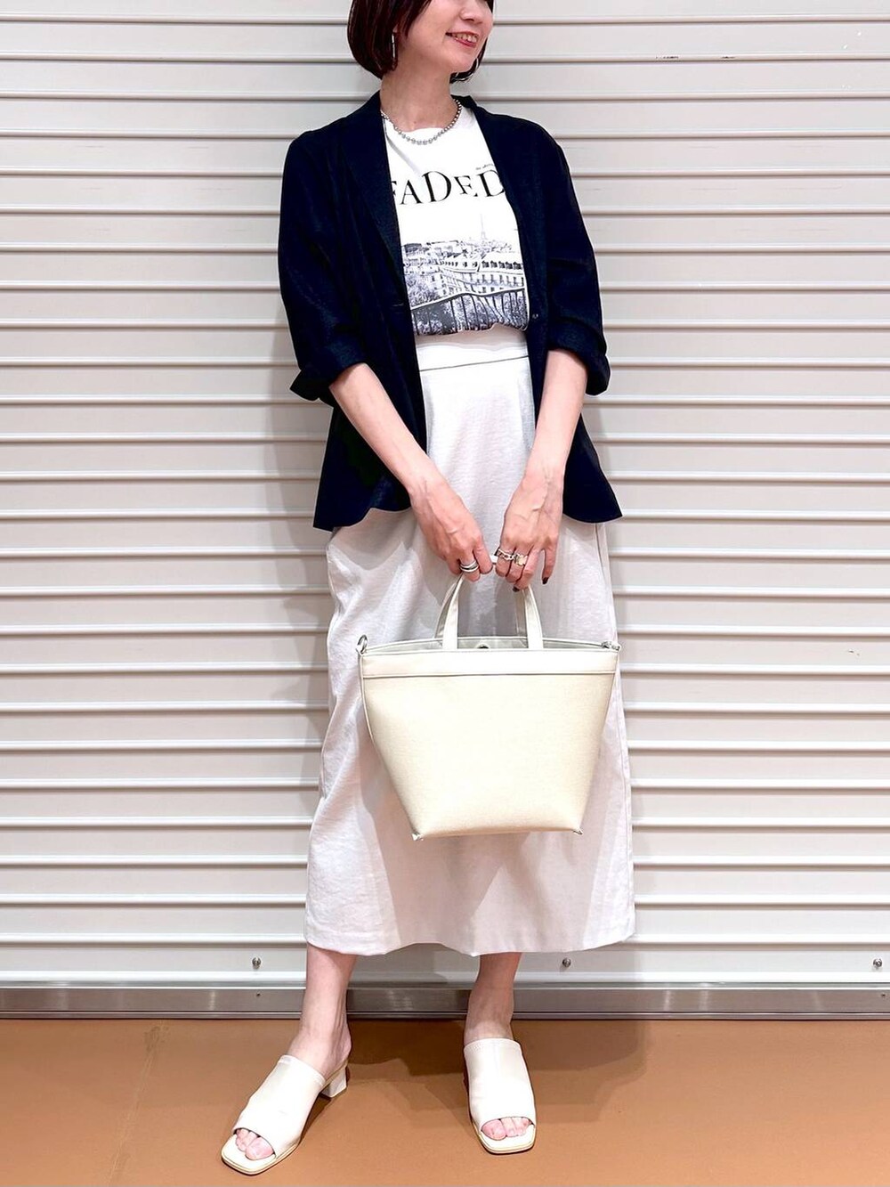 ホワイト系のサンダル、ホワイト系のトートバッグ、グレー系のスカートを着用したレディースの秋コーディネートの5枚目の写真