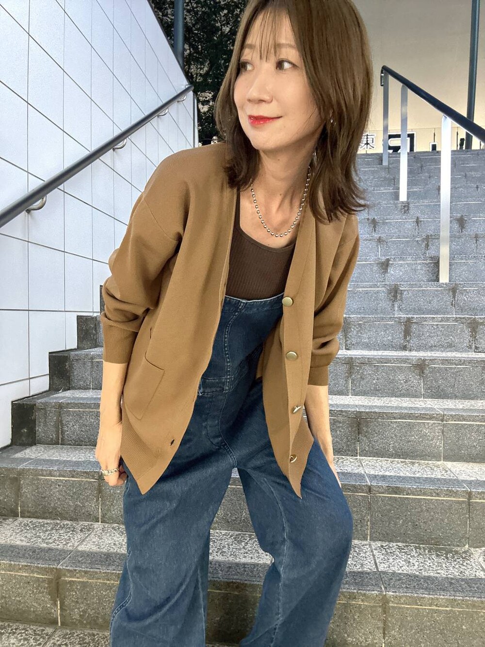 ブラウン系のニット/セーター、ブラウン系のカーディガン/ボレロ、ブルー系のサロペット/オーバーオールを着用したレディースの夏コーディネートの4枚目の写真