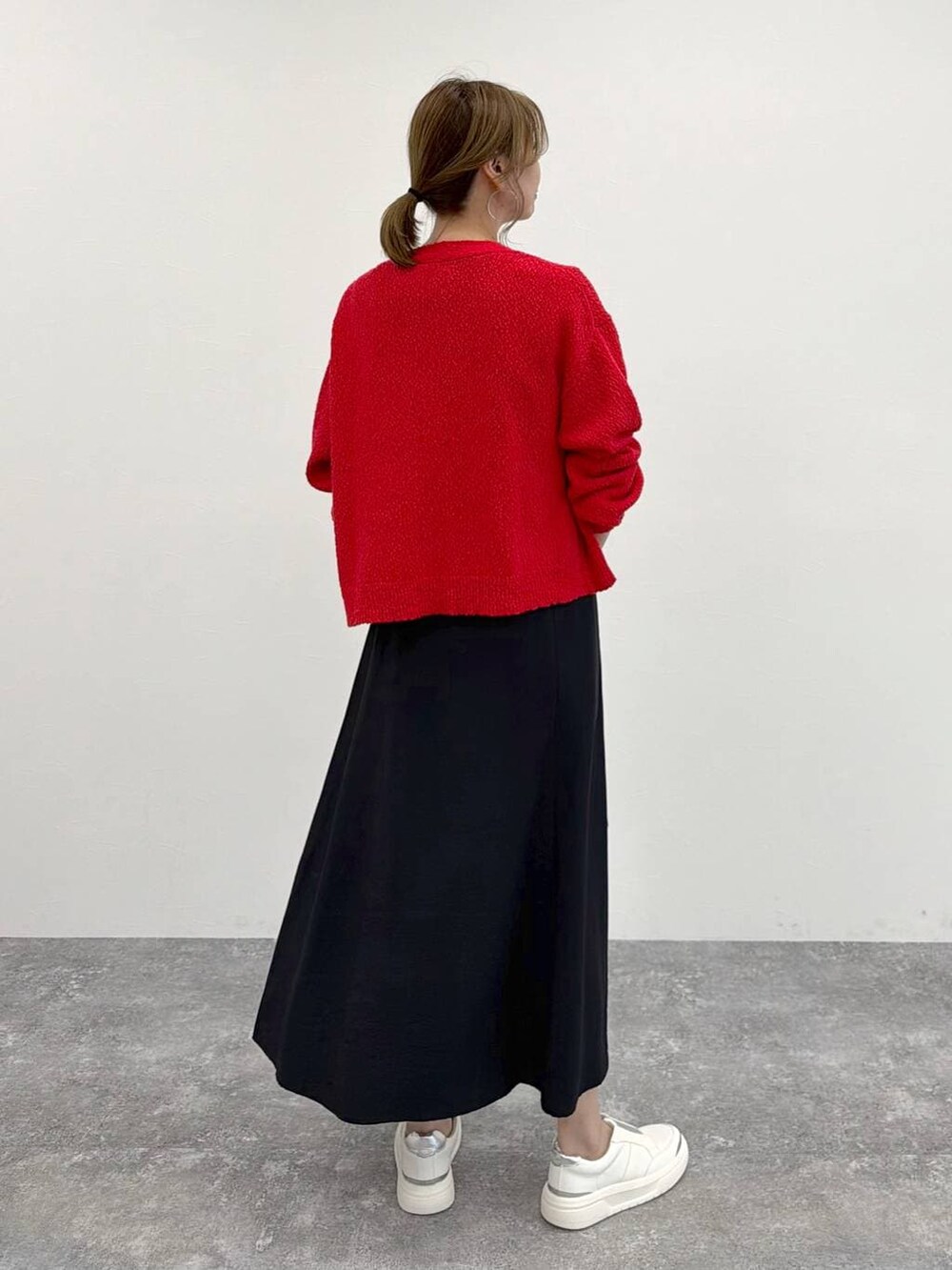 シルバー系のスニーカー、ブラック系のスカート、レッド系のカーディガン/ボレロを着用したレディースの春コーディネートの4枚目の写真