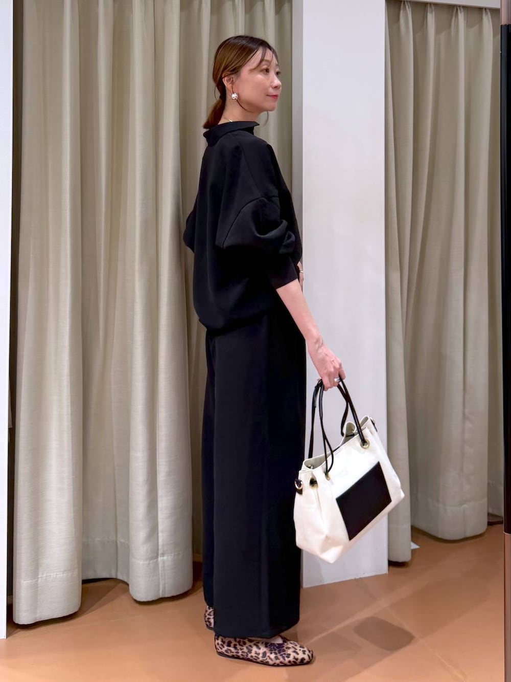 ブラウン系のパンプス、ホワイト系のトートバッグ、ブラック系のその他パンツを着用したレディースの冬コーディネートの3枚目の写真