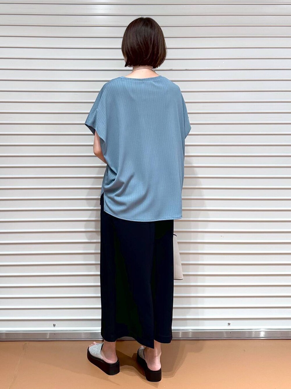 グリーン系のTシャツ/カットソー、シルバー系のサンダル、ブラック系のスカートを着用したレディースの秋コーディネートの4枚目の写真