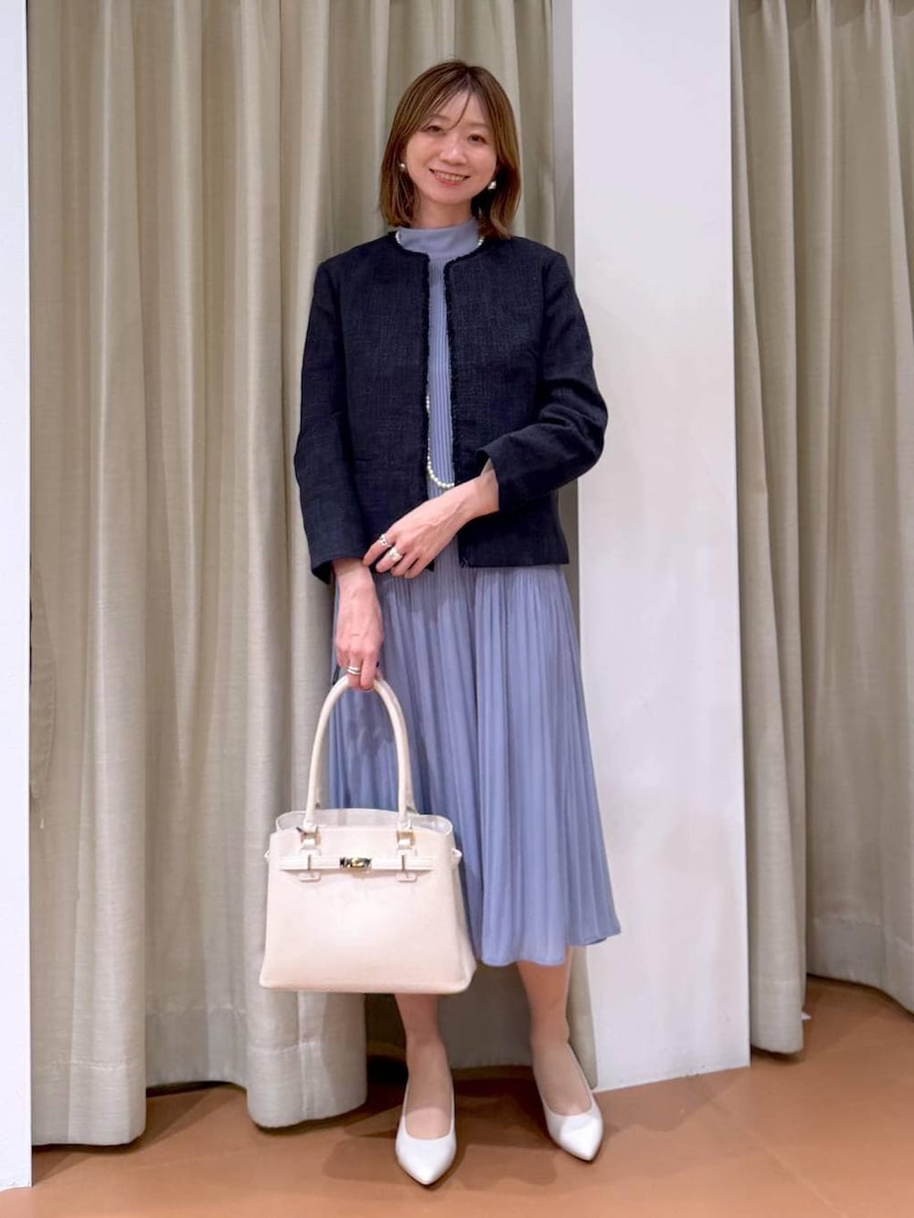 ベージュ系のパンプス、ブルー系のノーカラージャケット、ブルー系のワンピースを着用したレディースの冬コーディネートの6枚目の写真