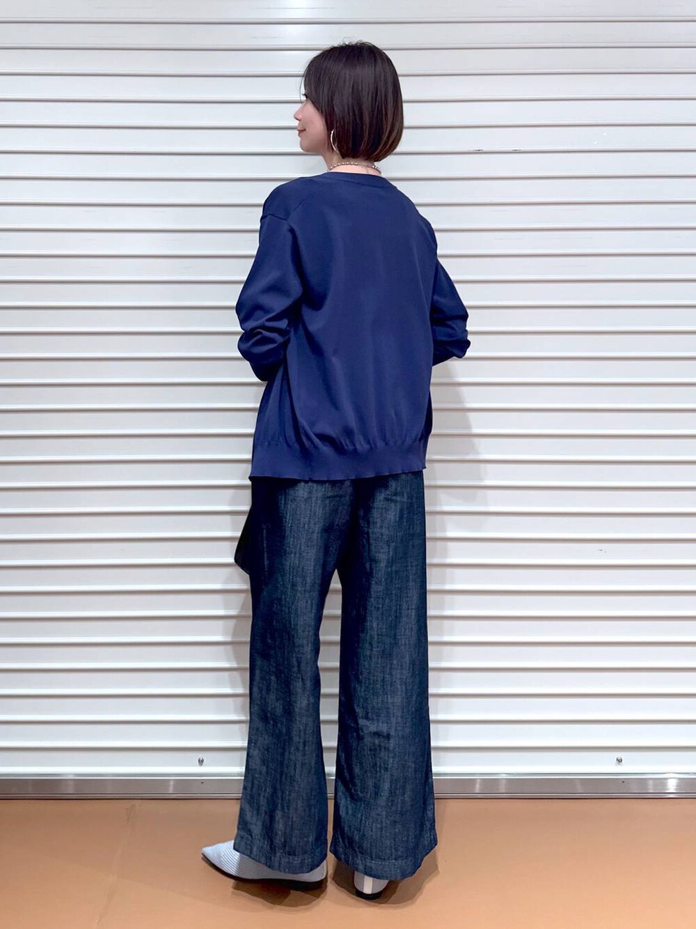 シルバー系のパンプス、ブルー系のデニムパンツ、ブラック系のショルダーバッグを着用したレディースの夏コーディネートの4枚目の写真